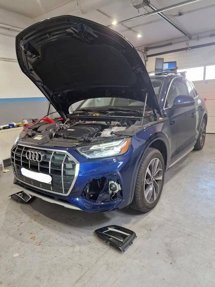 Audi Q5 z otwartą maską i zdjętymi kratkami zderzaka podczas prac przy czujnikach
